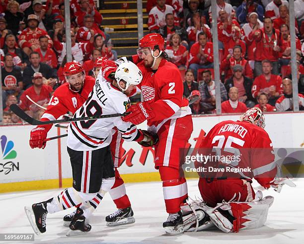 Jimmy Howard of the Detroit Red Wings makes a save as teamate Brendan Smith ties up Bryan Bickell of the Chicago Blackhawks during Game Six of the...