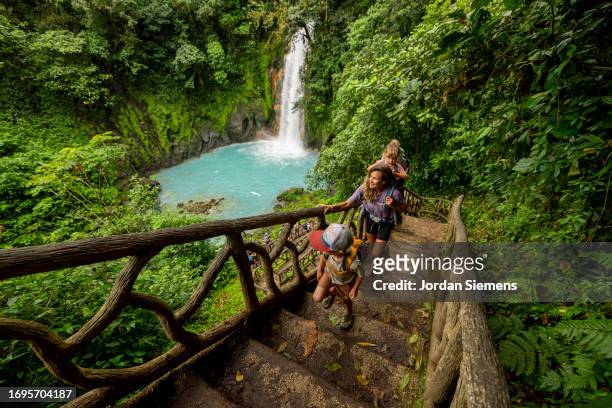 a family hiking at rio celeste waterfall in costa rica. - rainforest waterfall stock pictures, royalty-free photos & images