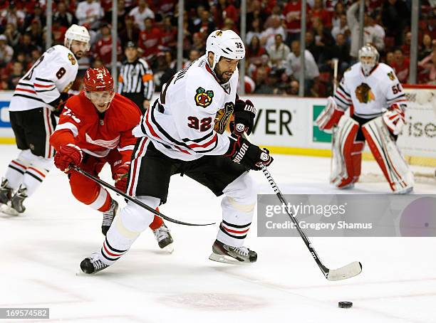 Michal Rozsival of the Chicago Blackhawks tries to control the puck in front of Cory Emmerton of the Detroit Red Wings in Game Six of the Western...