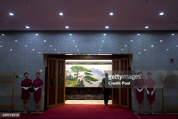 Hostesses stand outside a meeting room while a Chinese People's Liberation Army officer enters the room, before a meeting between U.S. National...