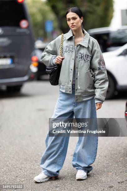 Guest is seen wearing a grey leather bomber embellished with littering details and patch, wide leg light blue jeans, white Nike sneakers and a black...