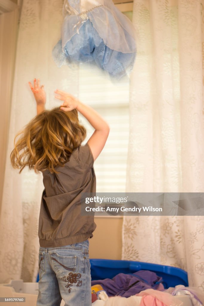 Girl finds dress in toy box.