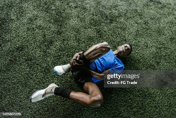 injured soccer player on a soccer field - soccer injury stock pictures, royalty-free photos & images