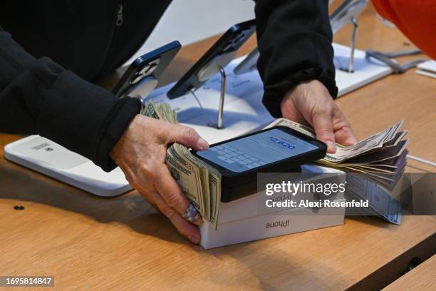 An apple employee counts cash after a person purchases Apple’s new iPhone 15 with 100 dollar bills during a launch event at the Fifth Avenue Apple...