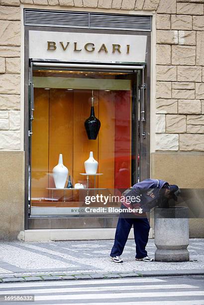 Man rummages through a public waste bin outside a Bulgari SpA luxury store in Prague, Czech Republic, on Monday, May 27, 2013. Czech policy makers...