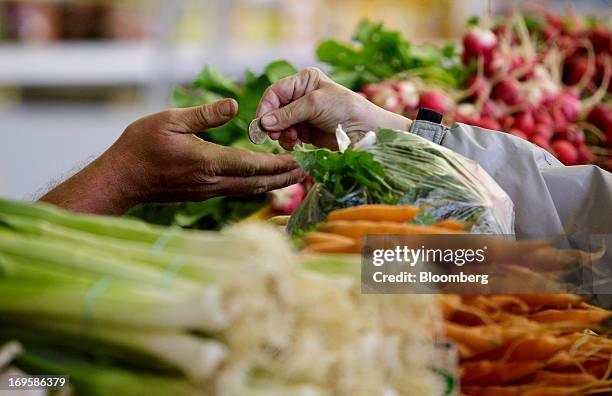 Customer, right, hands over a Czech koruna coin for payment at a vegetable stall in Holesovicka market hall in Prague, Czech Republic, on Monday, May...