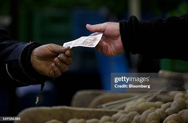 Customer hands over a two hundred denomination Czech koruna currency note at a vegetable stall in Holesovicka market hall in Prague, Czech Republic,...