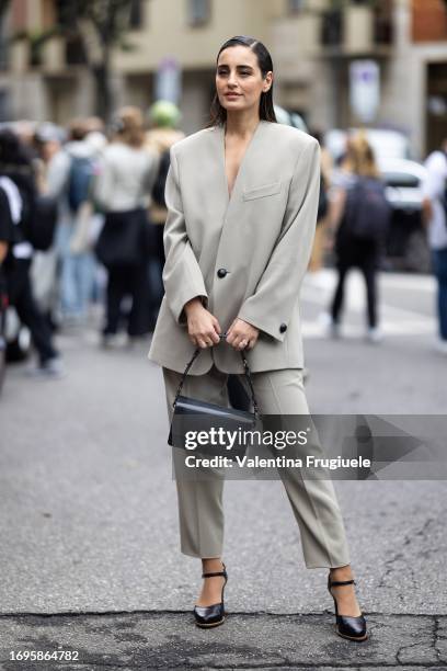 Guest is seen wearing a light beige oversized suit, black leather pumps and a black Tod's leather bag outside the Tod's show during Milan Fashion...