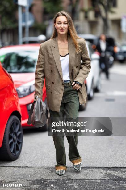Guest is seen wearing a white tank-top, a beige oversized blazer, green jeans, a grey bag and studded black ballerinas outside the Tod's show during...