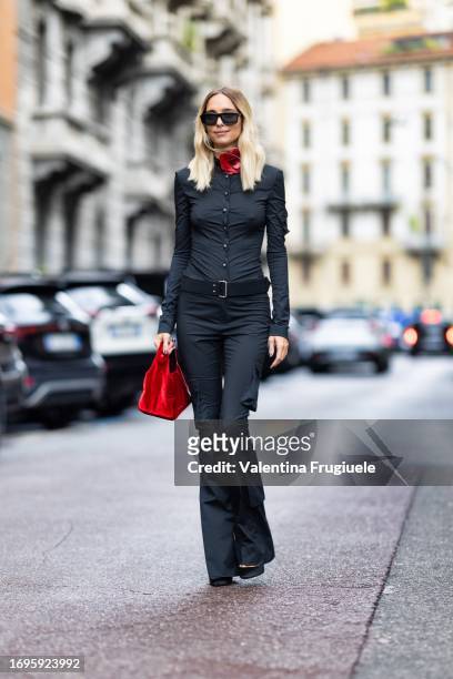 Candela Pellizza is seen wearing a grey shirt, a black belt, grey trousers, a red bag, black sunglasses and a red chocker with a 3d leather flower...