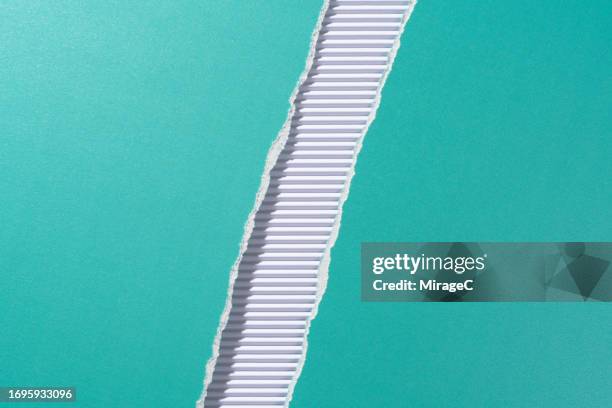 turquoise colored paper torn in half on white corrugated paper - bastelpapier stock-fotos und bilder
