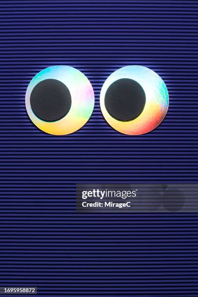 hologram googly eyes on purple corrugated paper - wackelaugen stock-fotos und bilder