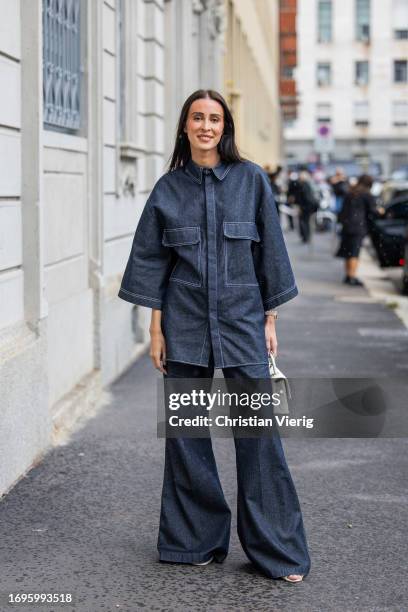 Elvira Jain wears oversized dark navy denim button shirt with short sleeves, flared jeans, white bag outside Calcaterra during the Milan Fashion Week...