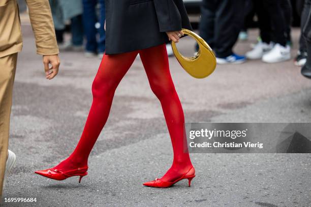 Guest wears golden Coperni bag, red tights outside Philosophy during the Milan Fashion Week - Womenswear Spring/Summer 2024 on September 22, 2023 in...