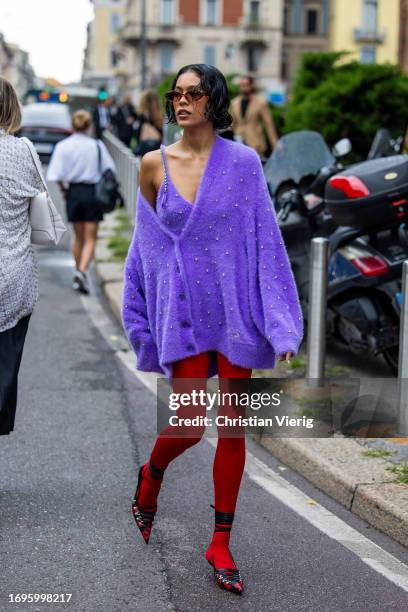 Guest wears purple oversized cardigan, red tights outside Philosophy during the Milan Fashion Week - Womenswear Spring/Summer 2024 on September 22,...
