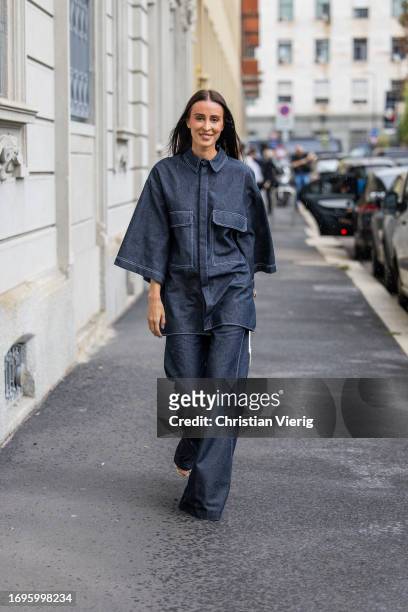 Elvira Jain wears oversized dark navy denim button shirt with short sleeves, flared jeans, white bag outside Calcaterra during the Milan Fashion Week...