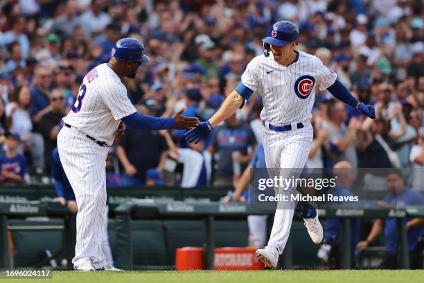 Jared Young of the Chicago Cubs celebrates with third base coach Willie Harris after hitting a two-run home run against the Colorado Rockies during...