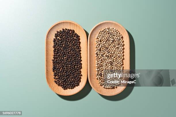 black pepper vs white pepper in wooden dish - side by side comparison stock pictures, royalty-free photos & images