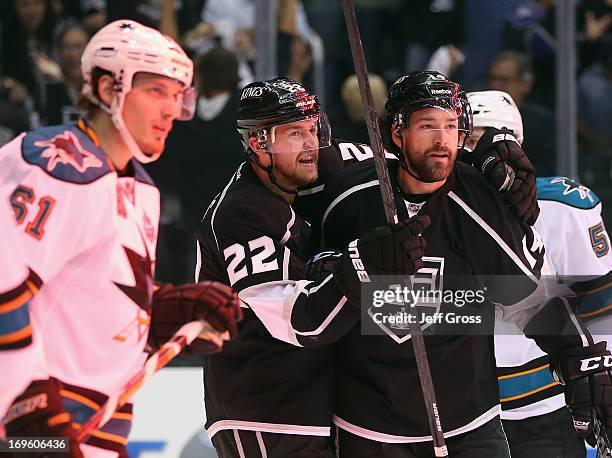 Justin Braun of the San Jose Sharks skates back to the bench, as Trevor Lewis and Justin Williams of Los Angeles Kings celebrate Williams' first goal...