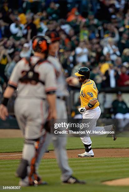 Derek Norris of the Oakland Athletics trot around the bases after hitting a two-run homer as catcher Buster Posey of the San Francisco Giants talks...