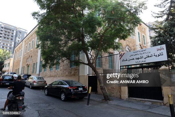 Man rides his motorcycle past the shuttered gate of a public school in Beirut on September 21, 2023. Lack of funding for the Lebanese school system...