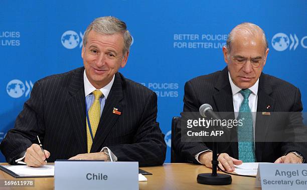 Chile Minister of Finance Felipe Larrain is flanked by OECD General Secretary Angel Gurria while signing a letter of intention to sign an OECD...