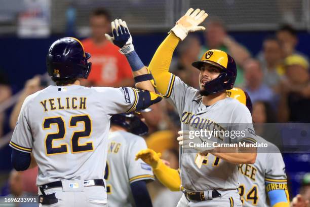 Christian Yelich high fives Willy Adames of the Milwaukee Brewers after hitting a three run home run during the sixth inning against the Miami...