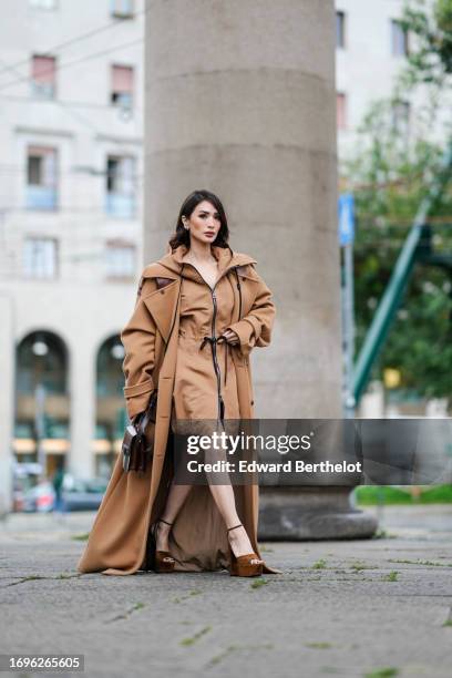 Heart Evangelista wears a brown / beige long trench coat with a hood , a beige raincoat worn as a short dress with front zipper, platform suede...