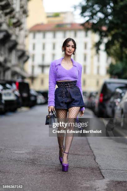 Heart Evangelista wears sunglasses, a purple wool top, blue denim shorts, fishnet tights, ,purple platform shoes outside Philosophy Di Lorenzo,...