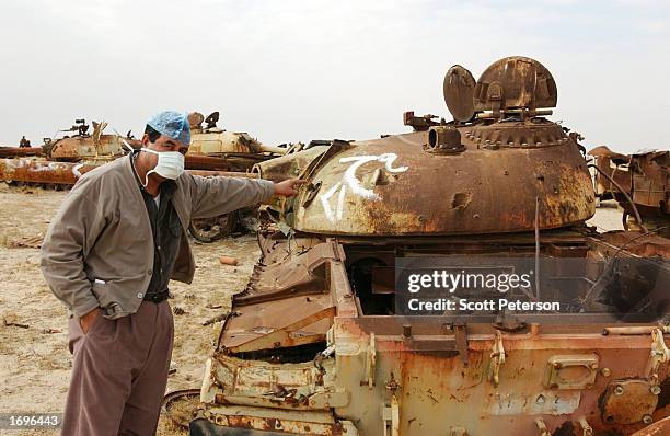 An Iraqi official points toward a DU impact point on a Iraqi tank destroyed during the 1991 Gulf War in a graveyard just north of Iraq's border with...