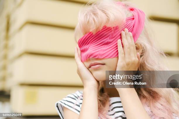 little girl covering eyes with pink ribbon. - dumb blonde stock pictures, royalty-free photos & images