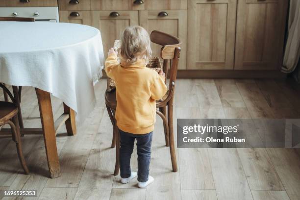 a child looking into basket in a kitchen. - laminat stock-fotos und bilder