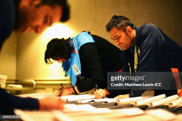 Dhoni of India signs cricket bats during an India Portrait Session at the Hyatt Hotel ahead of the ICC Champions Trophy at Edgbaston on May 30, 2013...