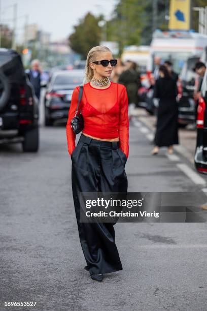 Caroline Caro Daur wears red transparent shirt, necklace, black wide leg pants, bag, sunglasses outside Gucci during the Milan Fashion Week -...