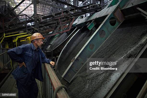 Worker watches as iron ore pellets pass through a machine at the Lebedinsky GOK iron ore mining and processing plant, operated by Metalloinvest...
