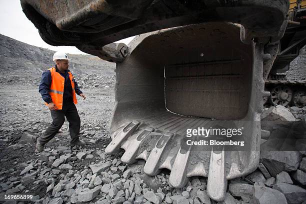 An operator checks an excavator bucket in the open pit of the Lebedinsky GOK iron ore mining and processing plant, operated by Metalloinvest Holding...
