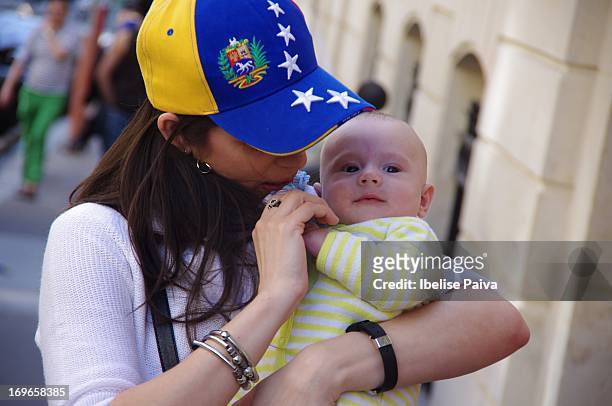 Woman wearing baseball cap with Venezuela's flag colors holds baby while waiting to vote at the Venezuelan presidential elections. Venezuela's...