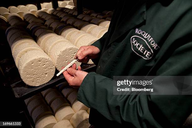 An employee takes a sample of Roquefort Societe 150years cheese from maturing racks in caves at the Lebrou-Roquefort plant, part of Groupe Lactalis...