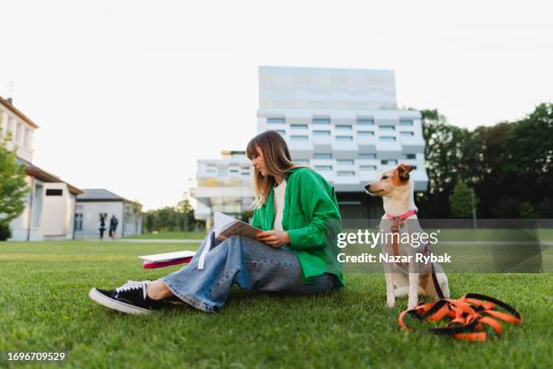 the beautiful female student makes some notes while studying sitting on the grass in the campus background - neurodiversity stock pictures, royalty-free photos & images