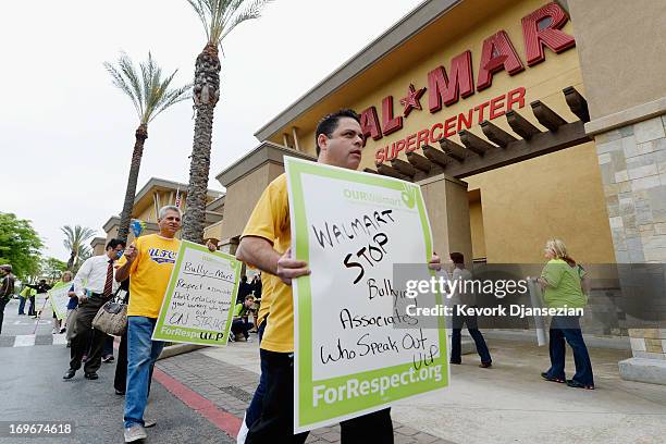 Walmart employees and their supporters walk a picket line to protest Walmart's retaliation against workers who speak out on May 30, 2013 in Pico...