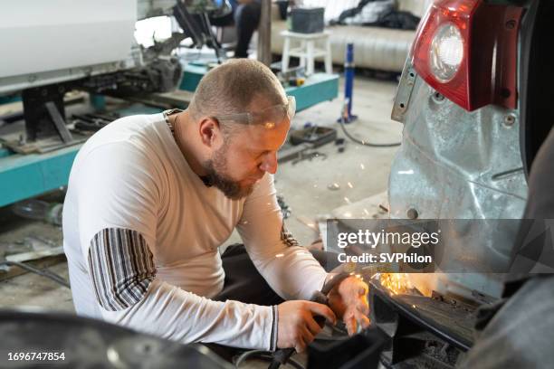 the mechanic uses welding to repair a damaged car. - ukraine people stock pictures, royalty-free photos & images