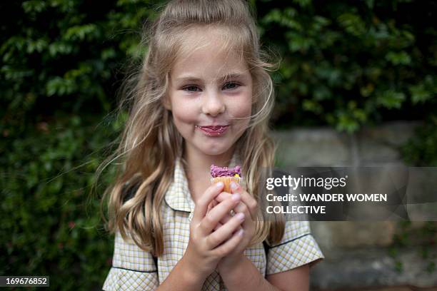 young girl in school uniform eating a cupcake - school dinner cake stock pictures, royalty-free photos & images