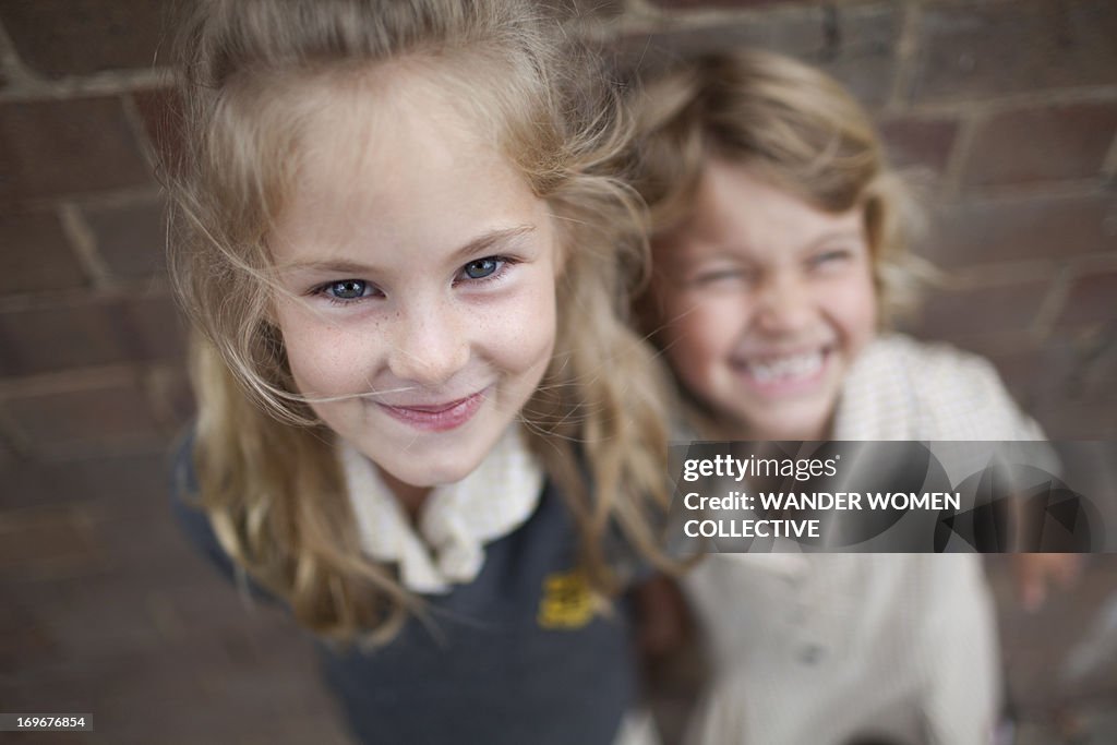 Two young girls smiling at camera school uniform