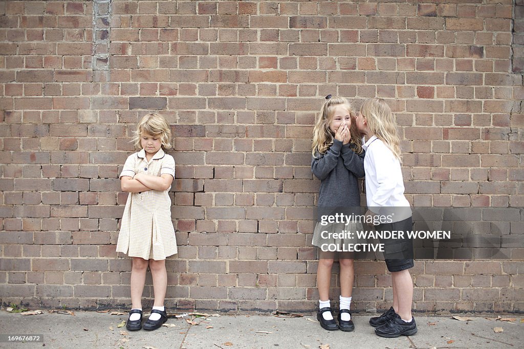 Bullying and whispering school kids in uniform