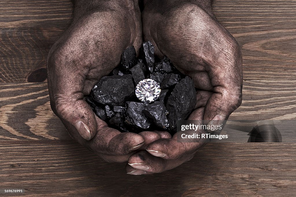 Solitaire diamond in hand full of coal