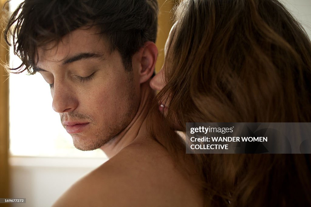 COuple kissing back of neck sitting on bed