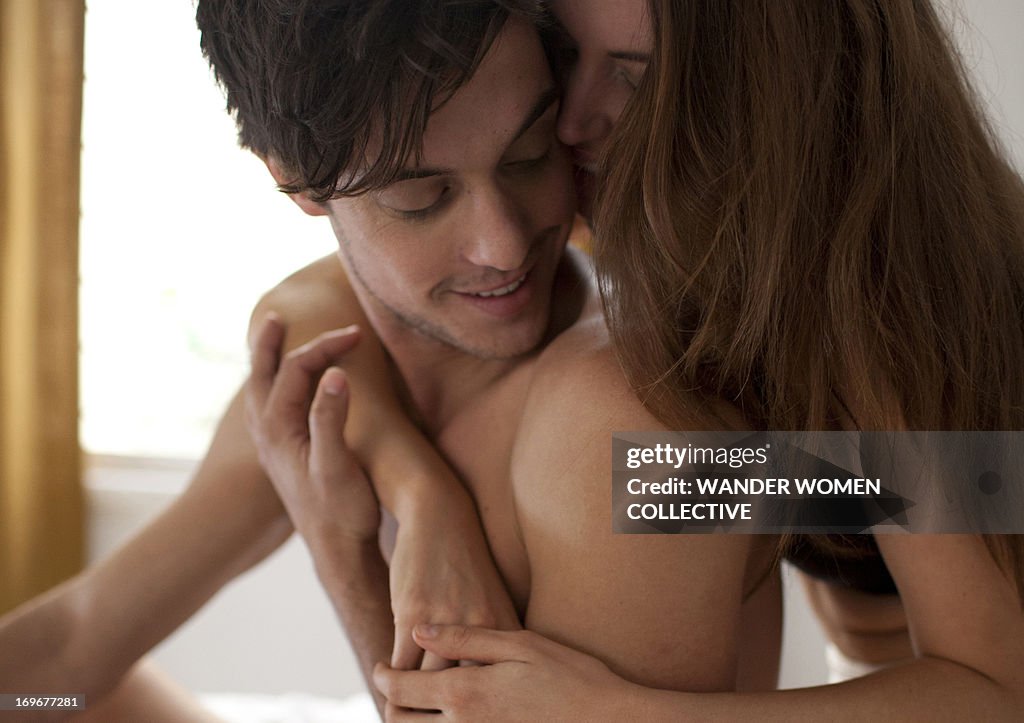 Couple cuddling sitting on bed