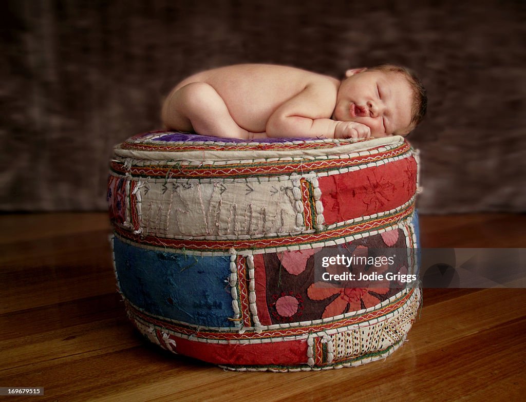 Newborn baby sleeping on colourful footrest