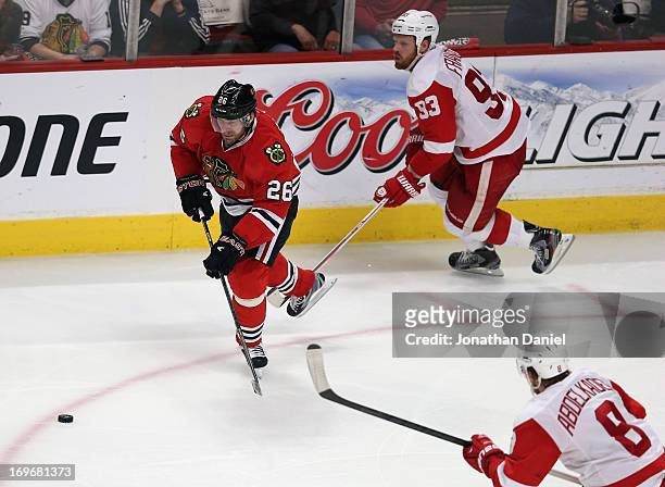 Michal Handuz of the Chicago Blackhawks chases the puck between Johan Franzen and Justin Abdelkader of the Detroit Red Wings in Game Seven of the...