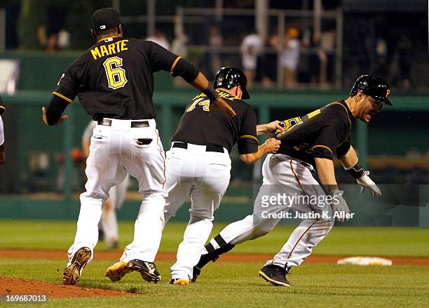 Russell Martin of the Pittsburgh Pirates is mobbed by teammates after hitting an RBI walk off single in the eleventh inning against the Detroit...